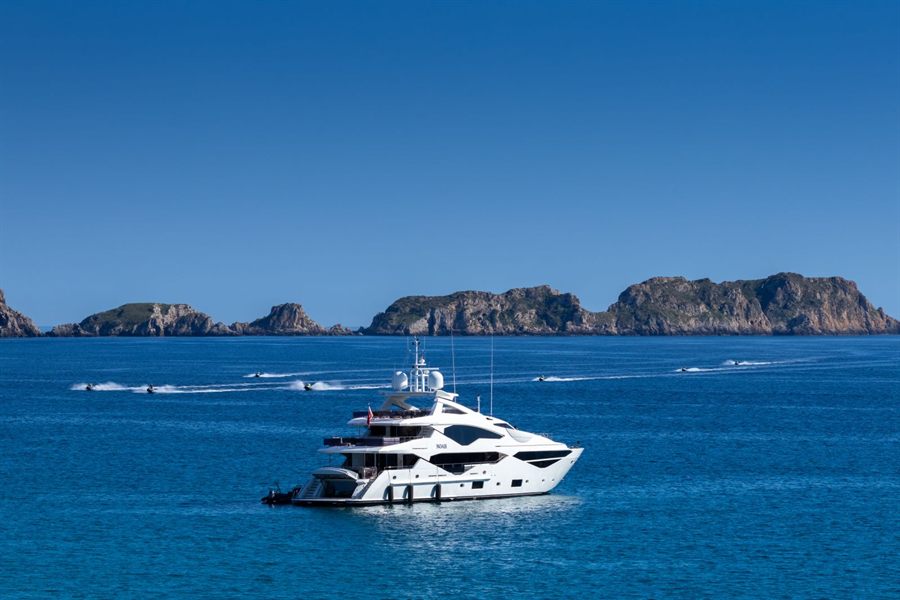 White yacht-style ship cruising past rocky islands on deep blue water