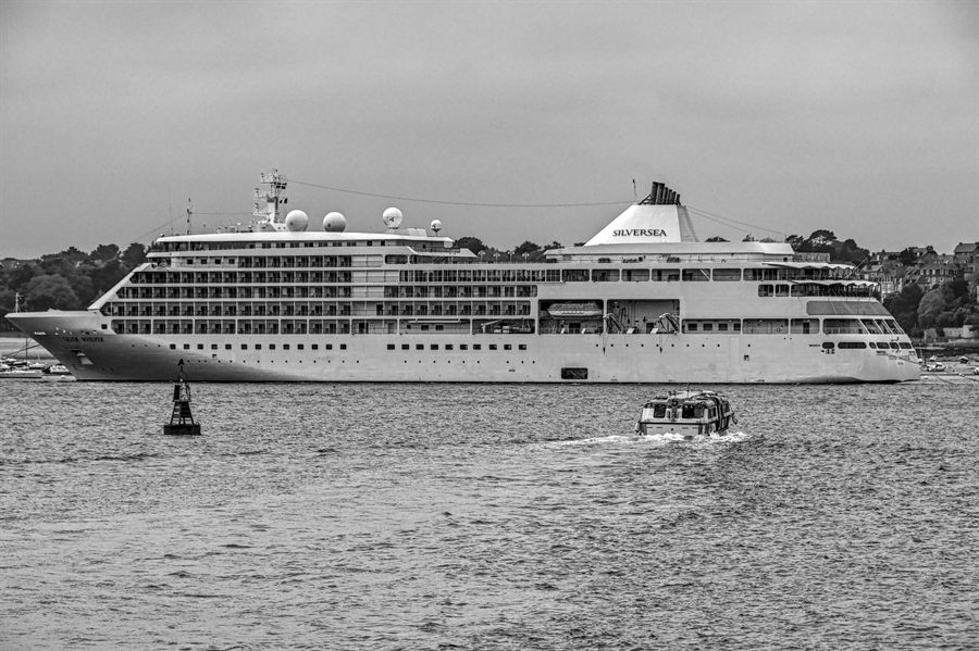 Silversea small luxury cruise ship sailing past a coastline in black and white