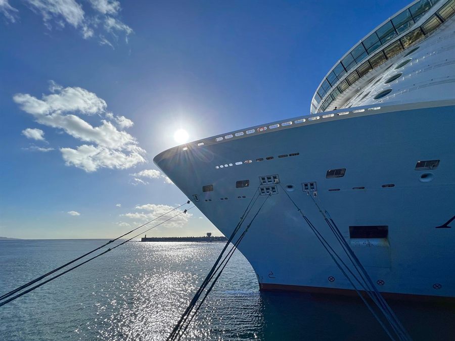Bow of a large cruise ship tied up at a sunny terminal