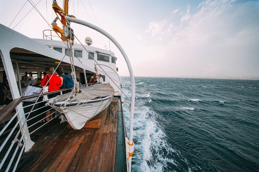 Ship deck with a lifeboat and rail above a choppy blue sea